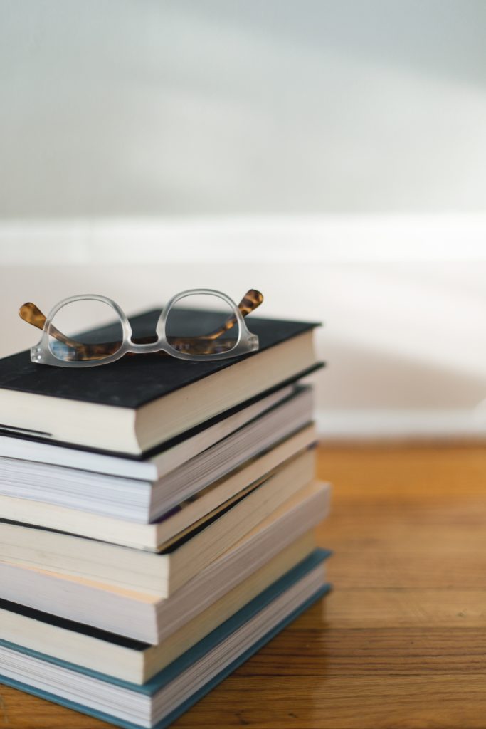 Stack of business and career related books with glasses on top.